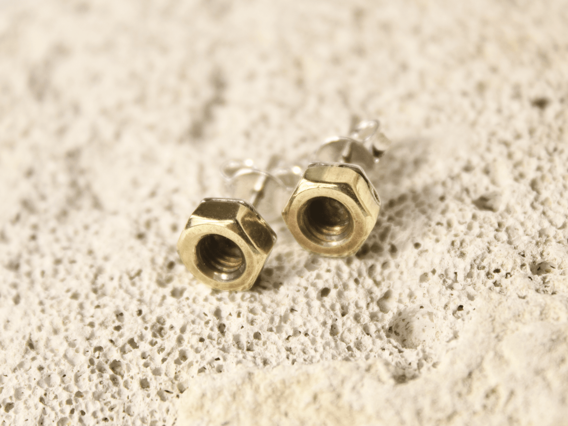 Orecchini a perno con bulloni in metallo dorato su base naturale rocciosa