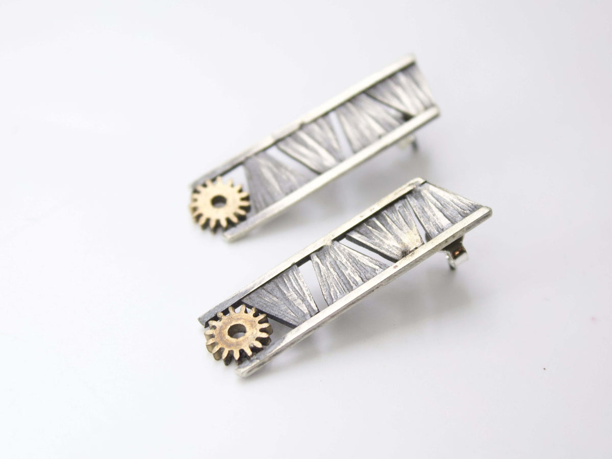 Orecchini pendenti in argento battuto a taglio increspature e ingranaggio finale con dettagli metallici.