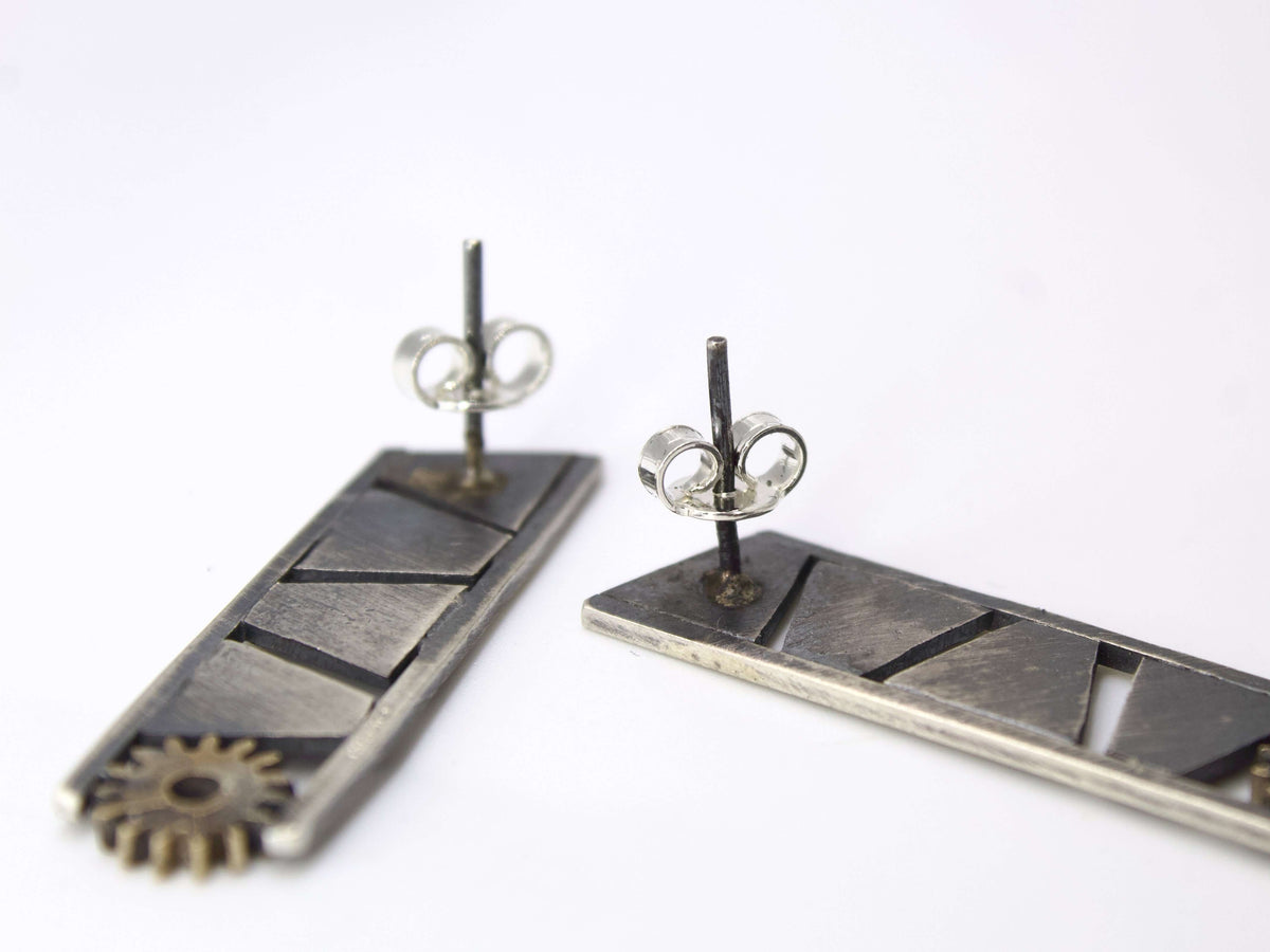 Orecchini pendenti in argento battuto a taglio increspature e ingranaggio finale, design elegante e moderno.