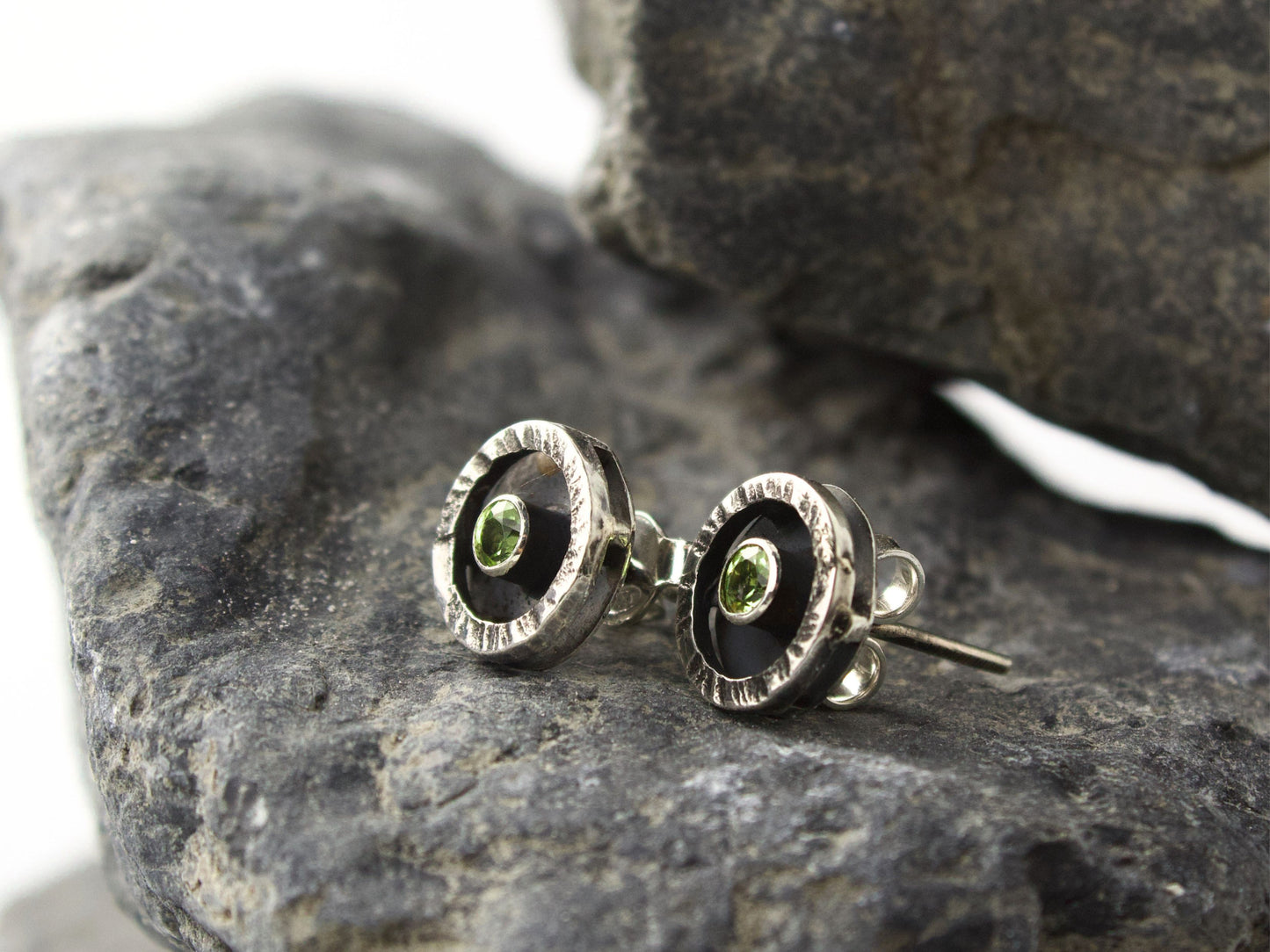 Orecchini con peridoto verde di 3mm incastonati in una cornice circolare argentata e martellata