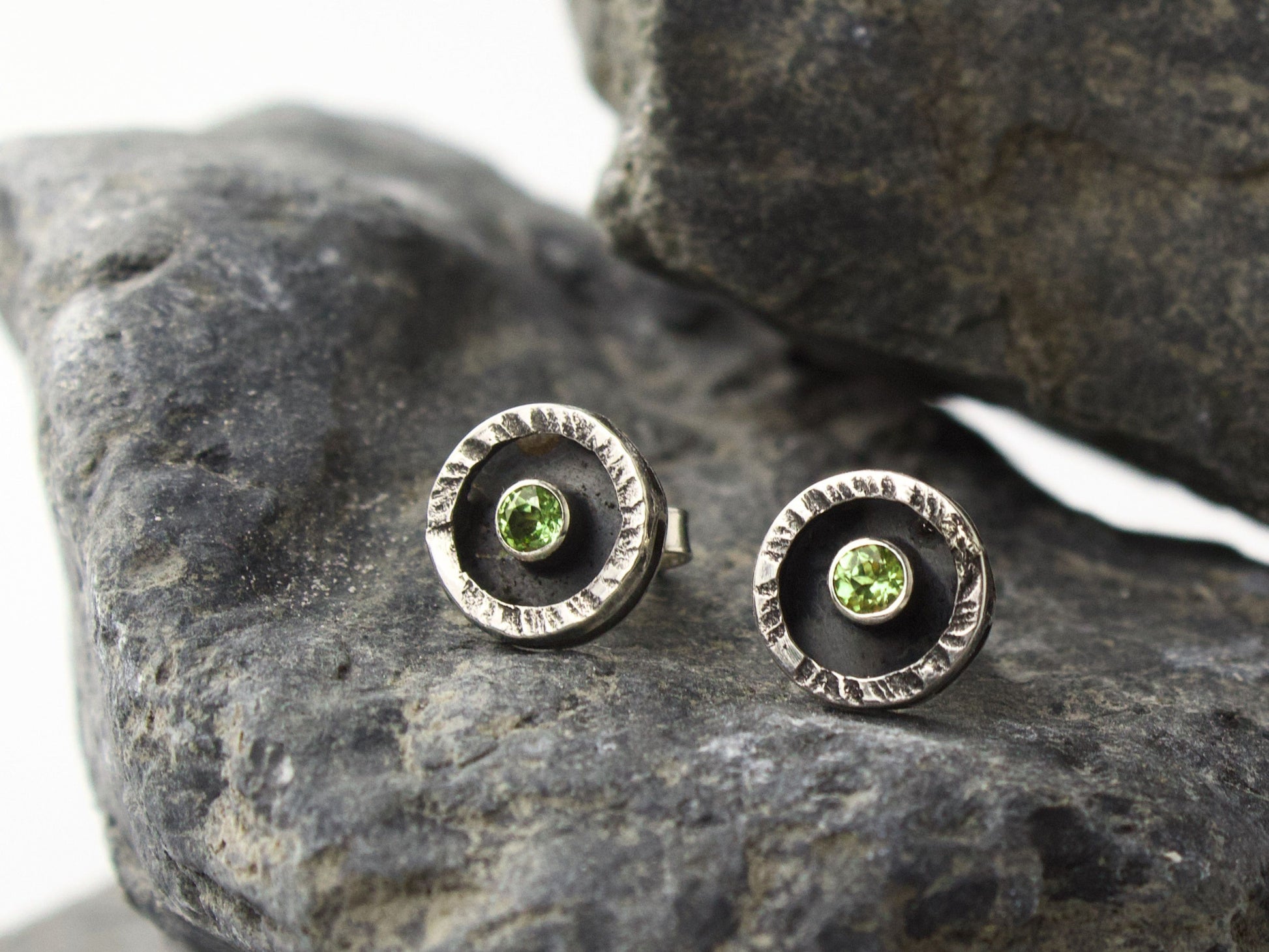 Orecchini in argento con peridoto centrale, montati in cerchi con superficie martellata.
