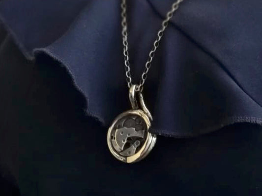 Collana Glimoire con pendente artigianale con meccanismo a vista su fondo scuro