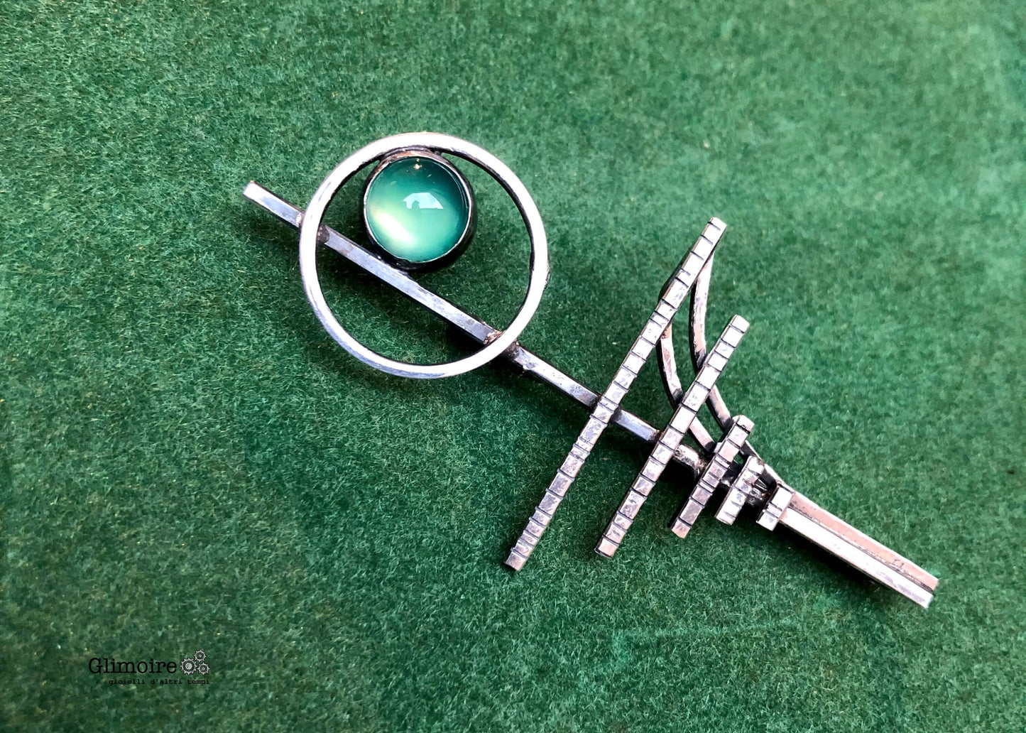 Spilla elegante con agata verde in argento con design geometrico su sfondo verde
