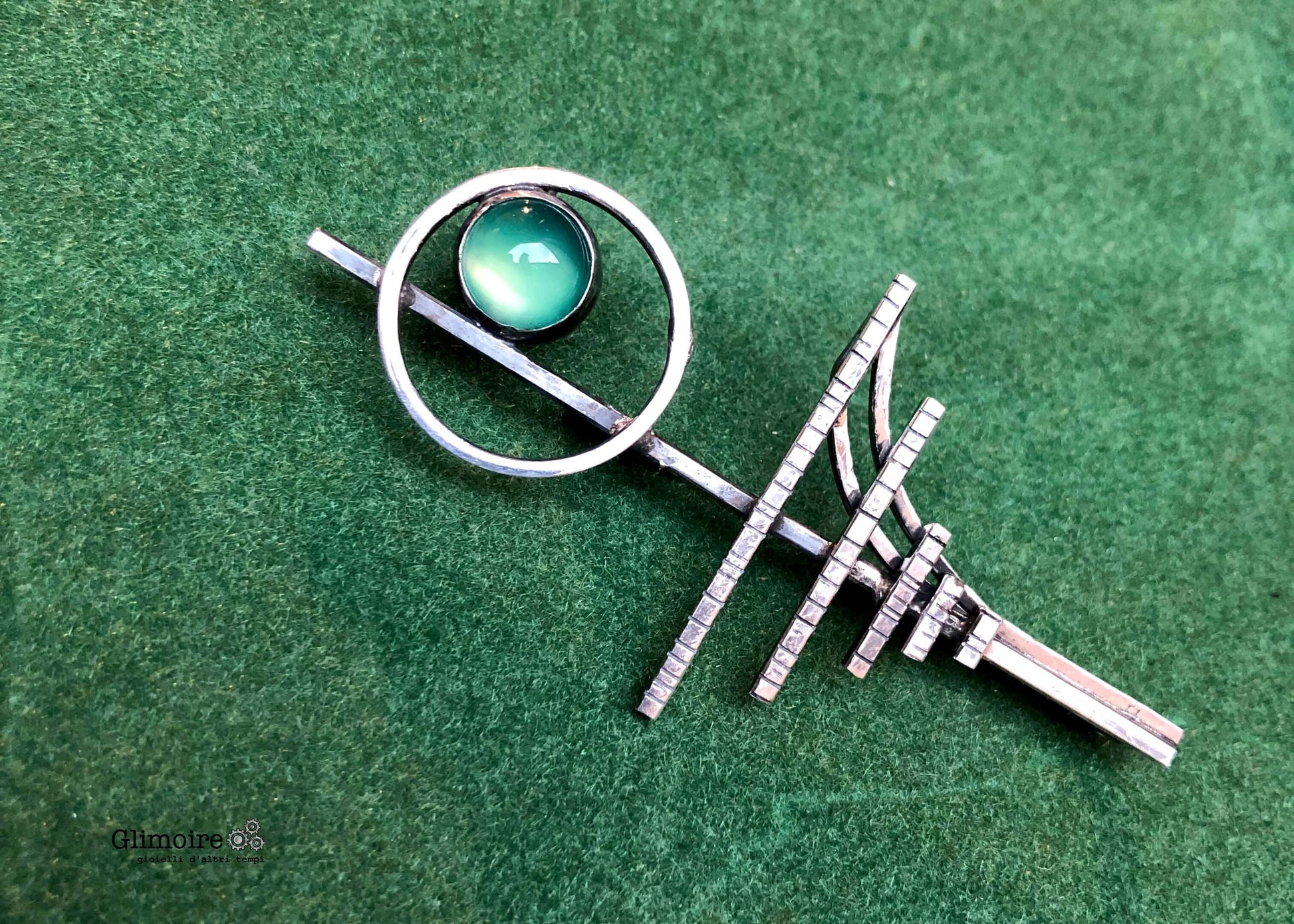 Spilla elegante con agata verde in argento con design geometrico su sfondo verde
