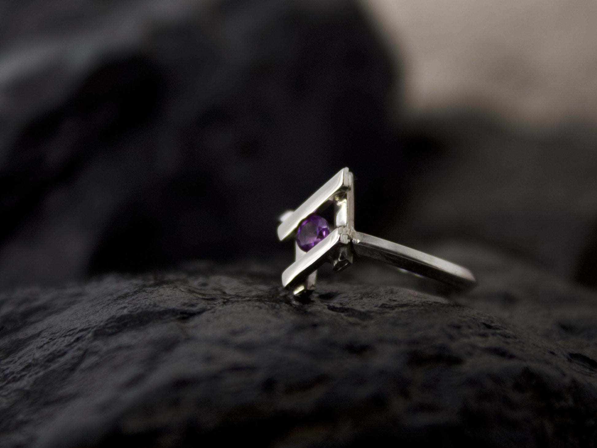 Anello Glimoire in argento con pietra viola incastonata su sfondo scuro