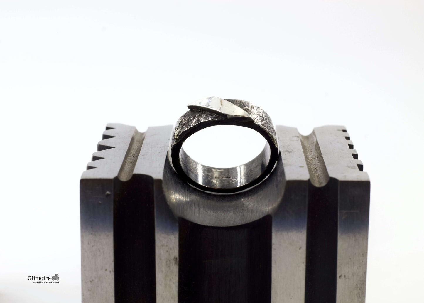 Anello artigianale Riverberi Glimoire, fascia in metallo lavorato con riflessi di luce.