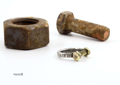 Anello dadi e bulloni Glimoire anello in argento con vite e dado su sfondo con bullone e dado arrugginiti
