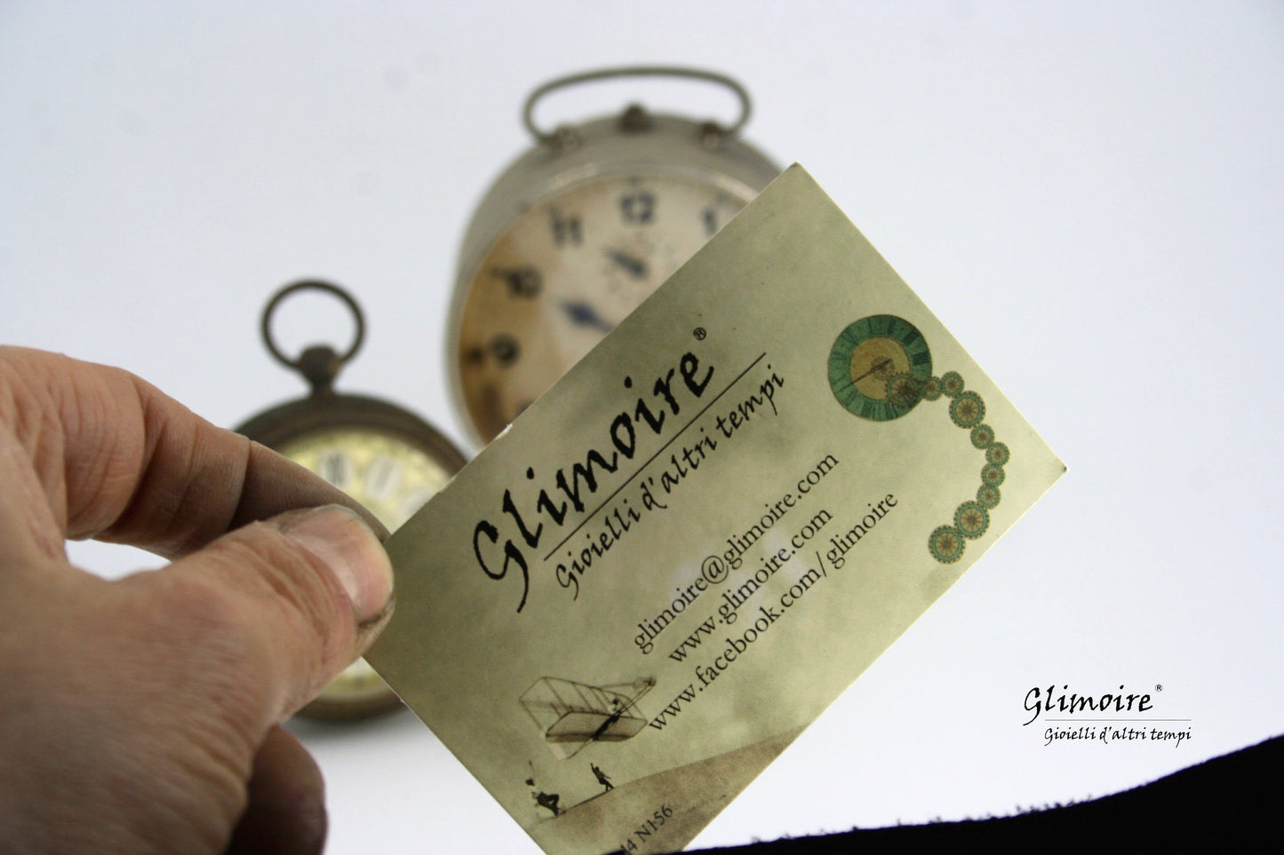 Biglietto da visita di Glimoire con orologi vintage sfocati sullo sfondo