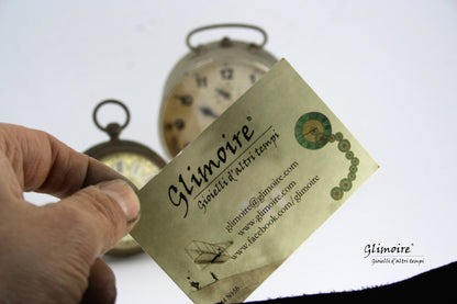 Biglietto da visita di Glimoire con orologi vintage sfocati sullo sfondo