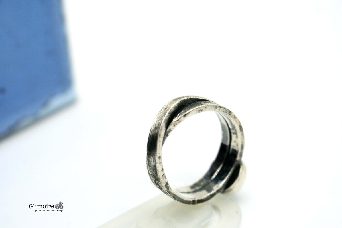 Anello intrecciato con pietra blu, vista laterale su sfondo chiaro