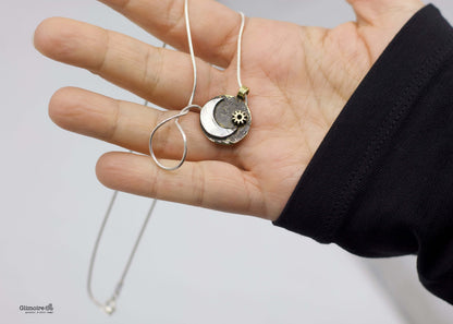 collana luna Glimoire mostrata in mano con pendente luna a mezzaluna e sole su disco metallico con catena sottile