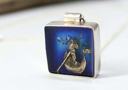 Collana con ciondolo gondoliere artigianale in argento su sfondo blu, dettaglio visibile del gondoliere