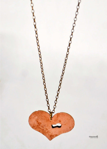 Collana con pendente a forma di cuore meccanico, in rame, con ingranaggi e una piccola serratura, appesa a una catena in ottone.