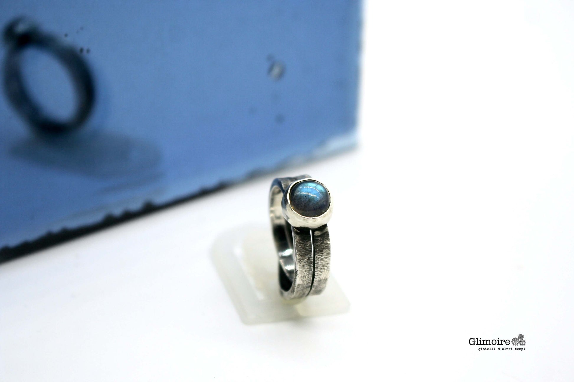 Anello intrecciato con pietra blu di Glimoire in argento con design elegante e riflessi luminosi