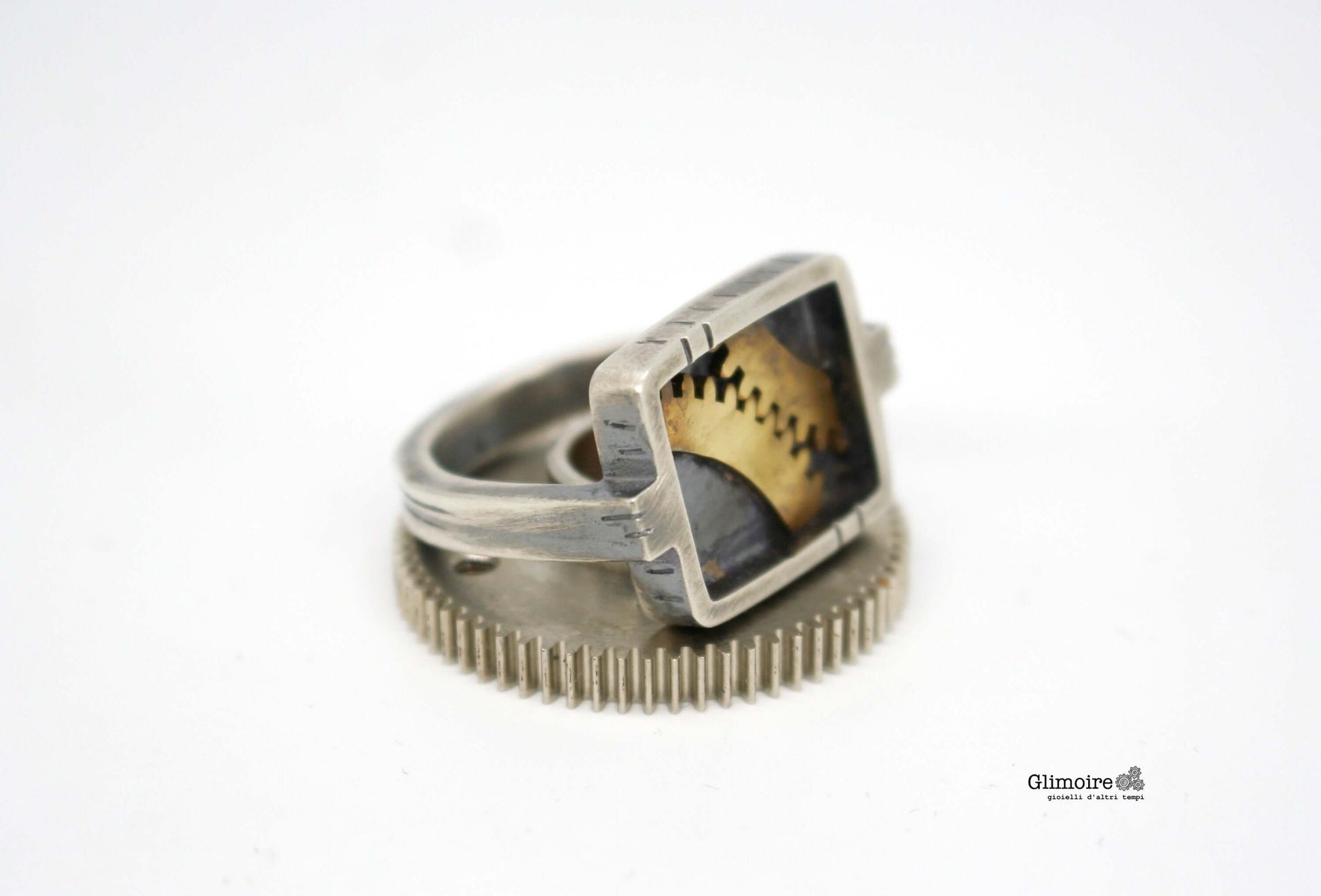 Anello industrial rettangolare Glimoire in argento con ingranaggi visibili all'interno design meccanico