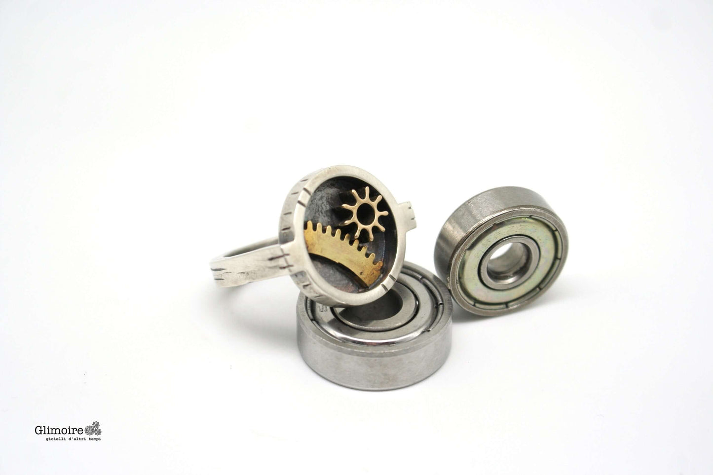 Anello industrial rettangolare Glimoire con ingranaggi in ottone su sfondo bianco