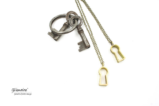 Collana con serratura Glimoire pendente a forma di chiave dorata su sfondo bianco
