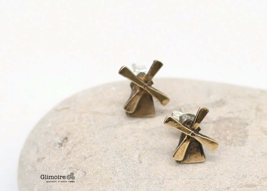 Orecchini mulini fatti a mano in metallo bronzato firmati Glimoire su sfondo chiaro