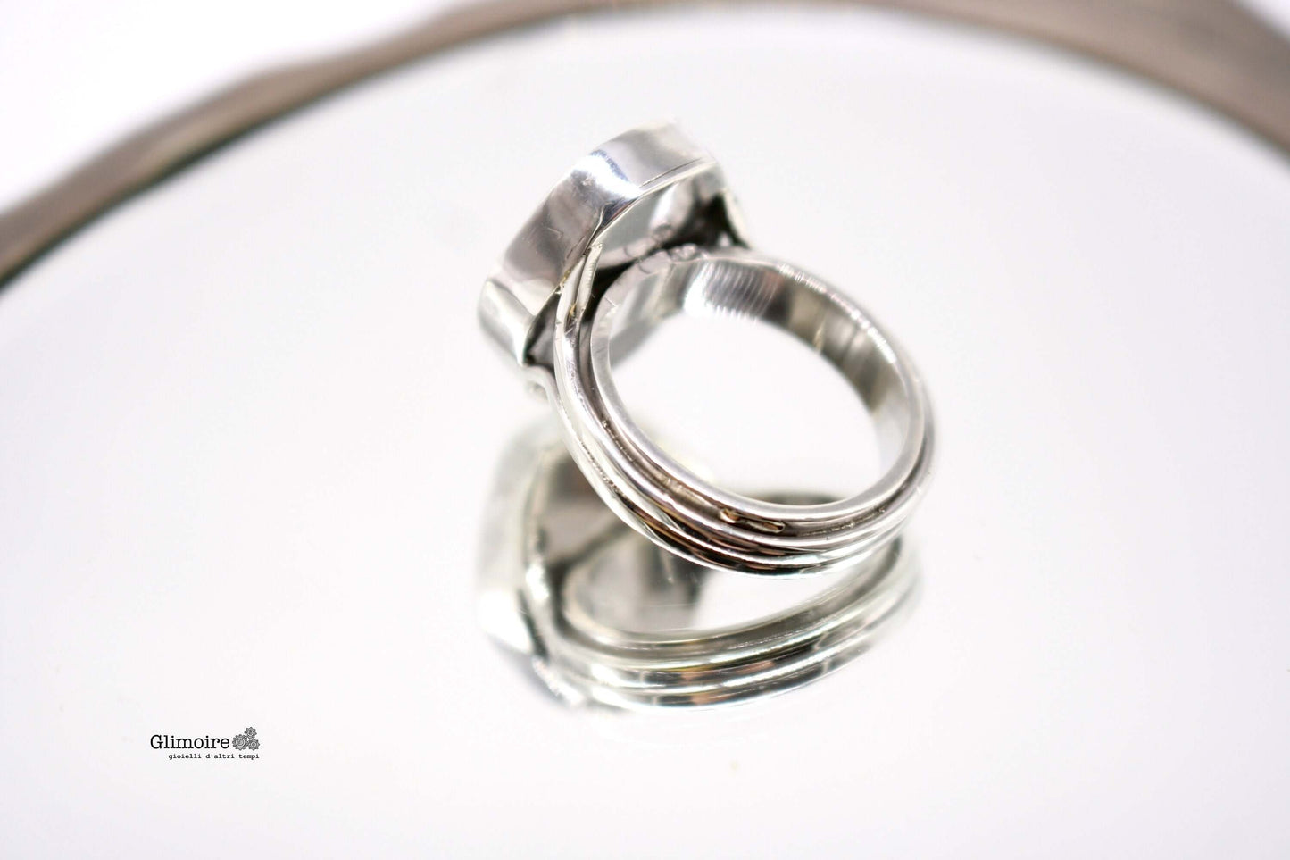 Anello in argento con orologio firmato Glimoire su superficie riflettente