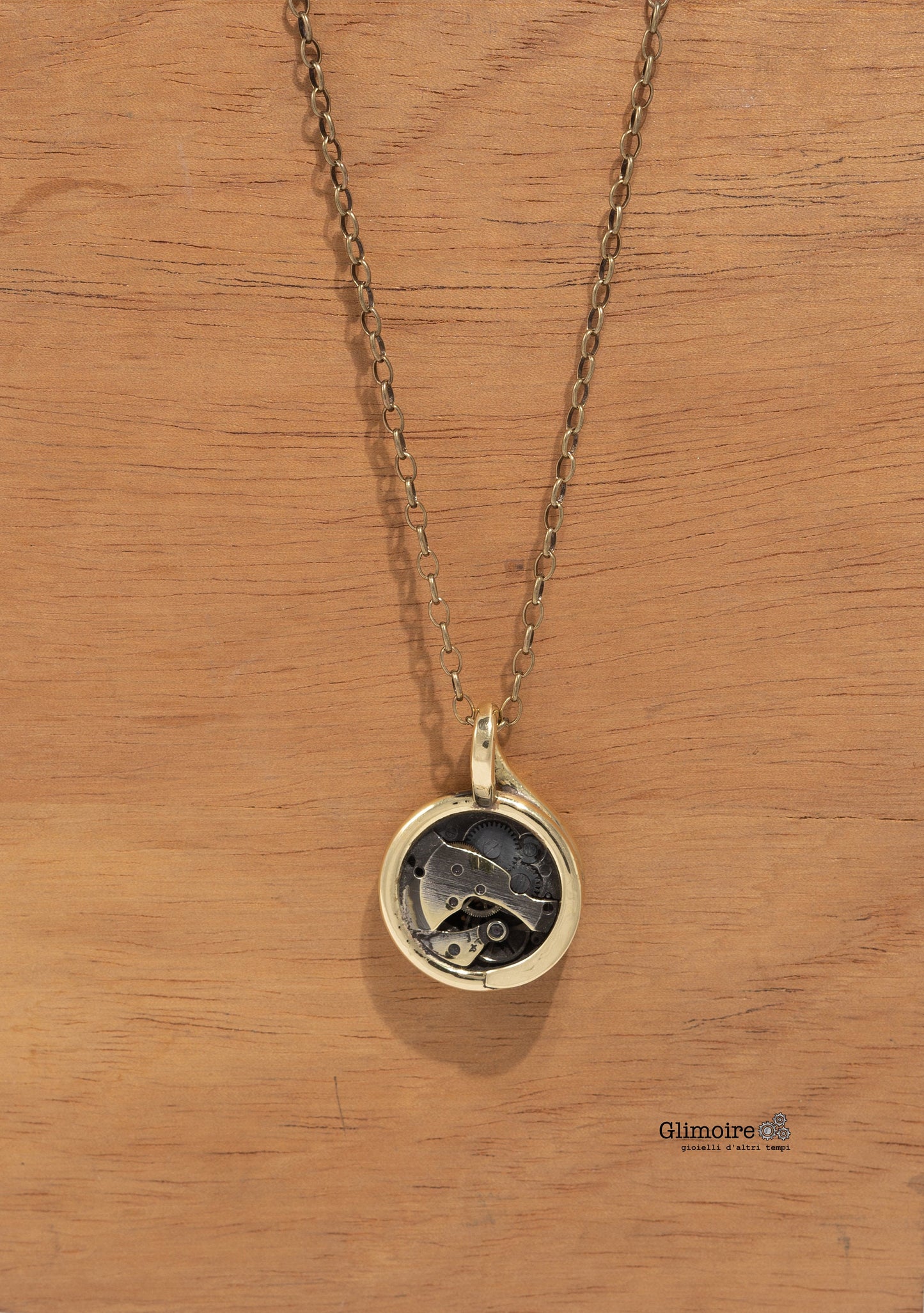 Collana Glimoire con pendente artigianale con meccanismo in design vintage su sfondo legno