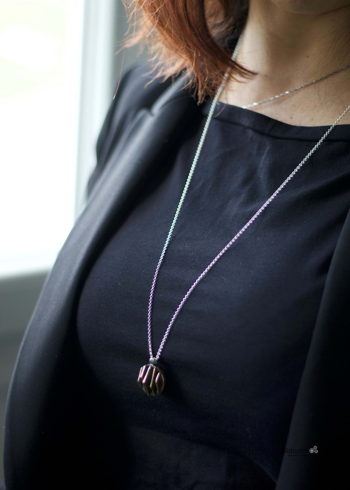 Collana Glimoire con pendente dal design geometrico in bronzo indossata su una camicetta nera
