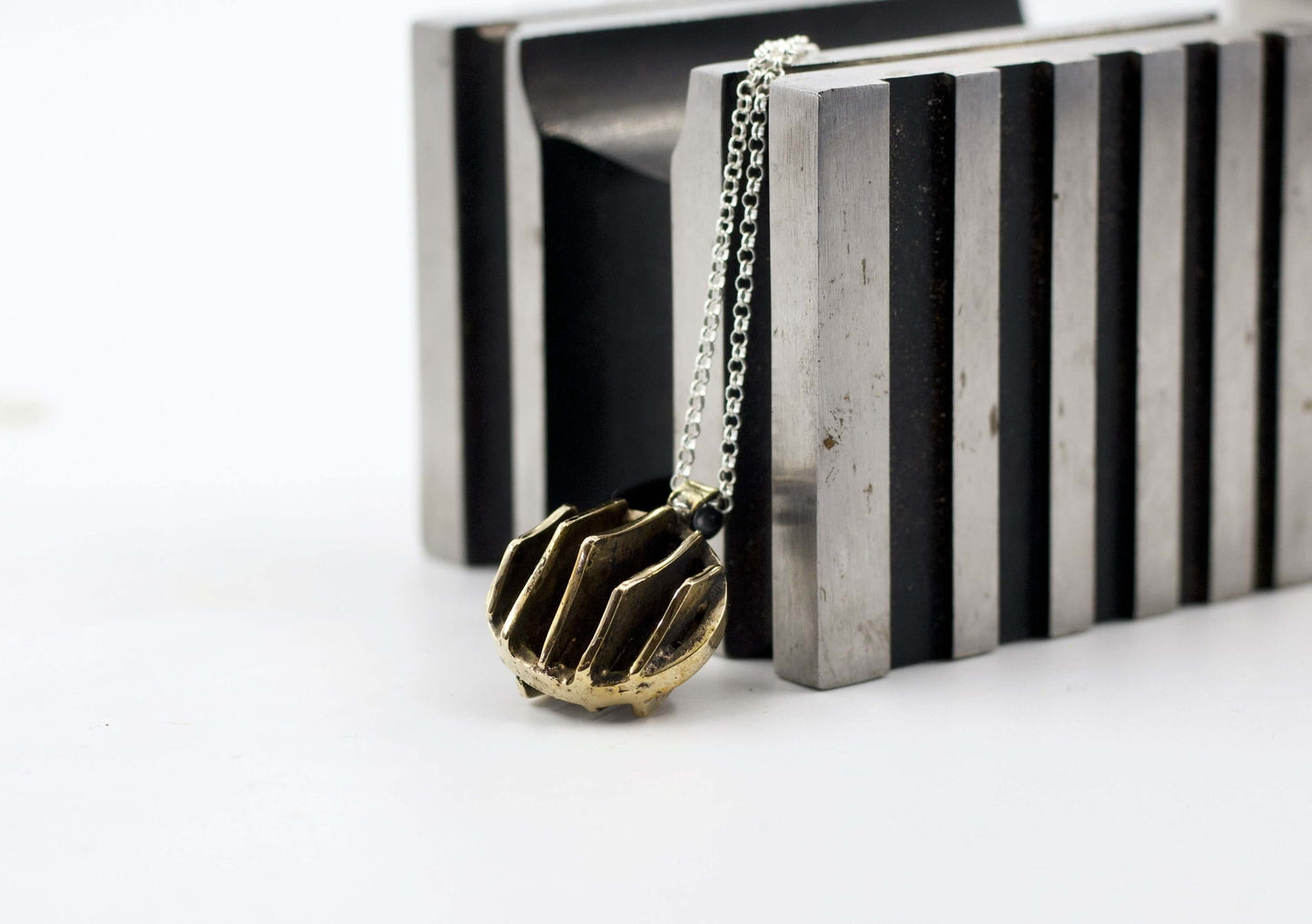 Collana Glimoire con pendente dal design geometrico in bronzo su fondo neutro