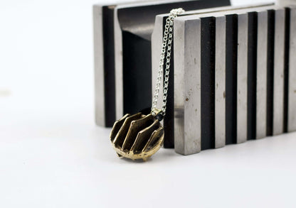 Collana Glimoire con pendente dal design geometrico in bronzo su fondo neutro