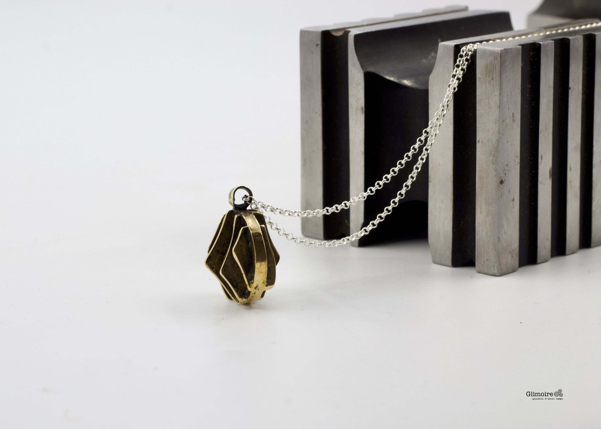 Collana con pendente dal design geometrico in bronzo su sfondo di metallo