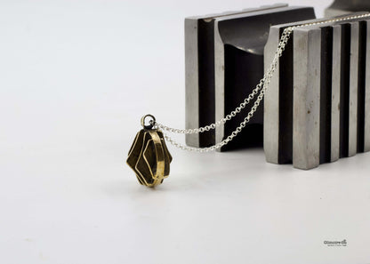 Collana con pendente dal design geometrico in bronzo su sfondo di metallo