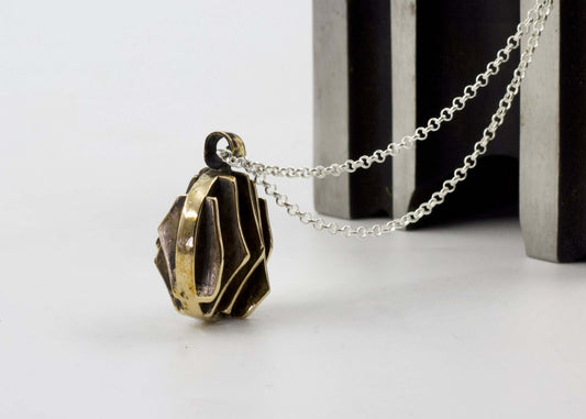 Collana con pendente dal design geometrico in bronzo appeso a una catena argentata